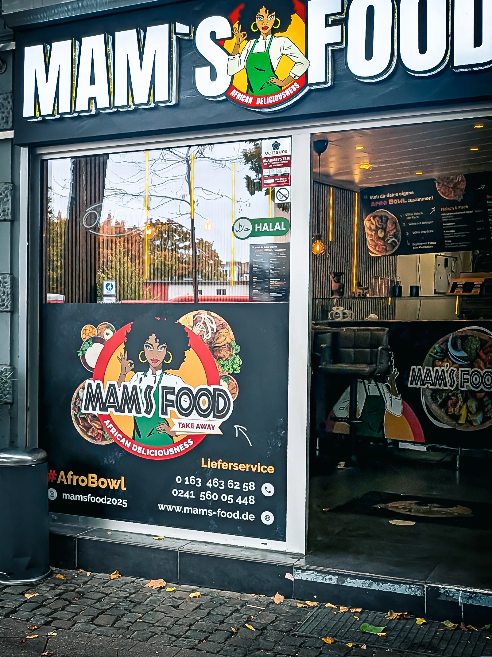 Mam's Food Schaufenster in Aachen — vollflächige Folie mit verfeinertem Logo »Mam's Food — African Deliciousness« und Kontaktdaten, Corporate Design von Emrach aus Aachen